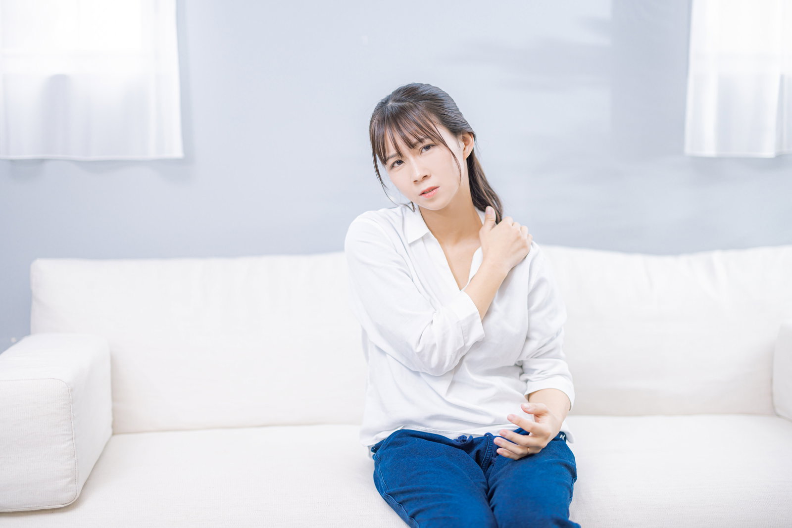 肩こりで肩を押さえる女性［モデル：本坊実結］