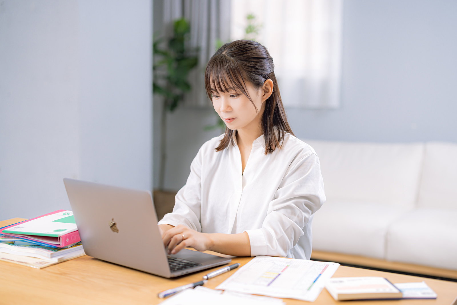 白いシャツを着た女性がノートパソコンで経費データを入力している［モデル：本坊実結］