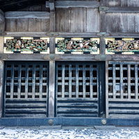 冬の日光東照宮で見る格子戸と上部の三猿の彫刻装飾と雪景色の写真