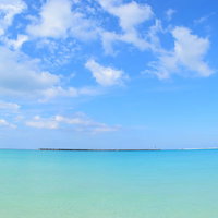 沖縄の透明なエメラルドグリーンの海と遠くに見える防波堤の写真