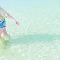 沖縄の穏やかな透明な海の浅瀬を歩く女性のリゾート風景の写真