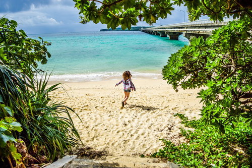 南の島で羽を広げる女性、宮古ブルーのビーチにて