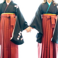 手を繋いで卒業を迎える紺色着物と赤い袴姿の女子たちの写真