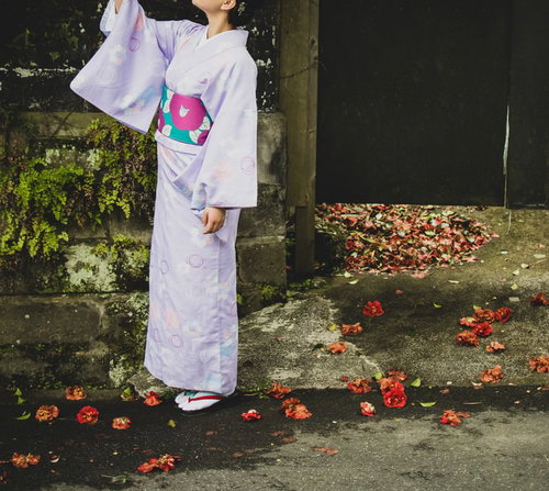 暖簾の前で天を仰ぐ浴衣姿の女性が見上げる夏の風情