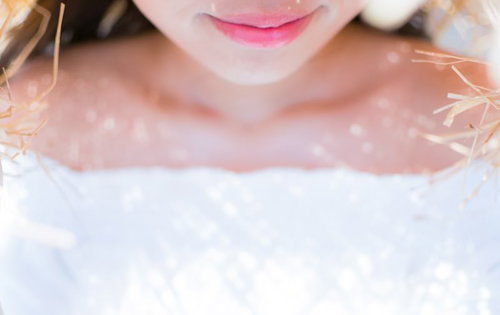 麦わら帽子の影からそっと微笑む口元とピンク色の唇