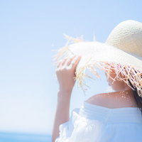 麦わら帽子で日焼け対策する女性の夏のファッションの写真
