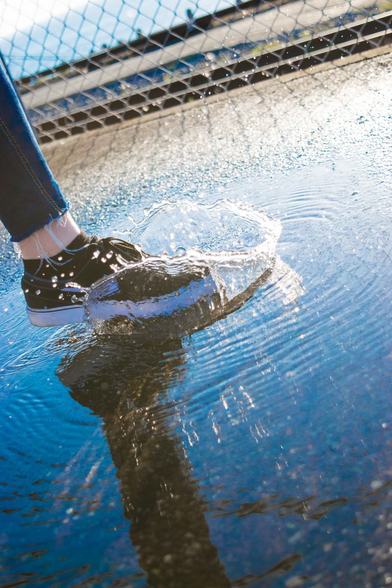 水たまりを踏んで水が跳ね上がる足元