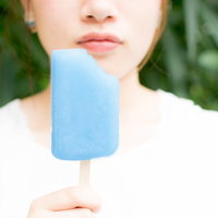 ソーダ味の青いアイスバーを食べる女性の夏の時間の写真