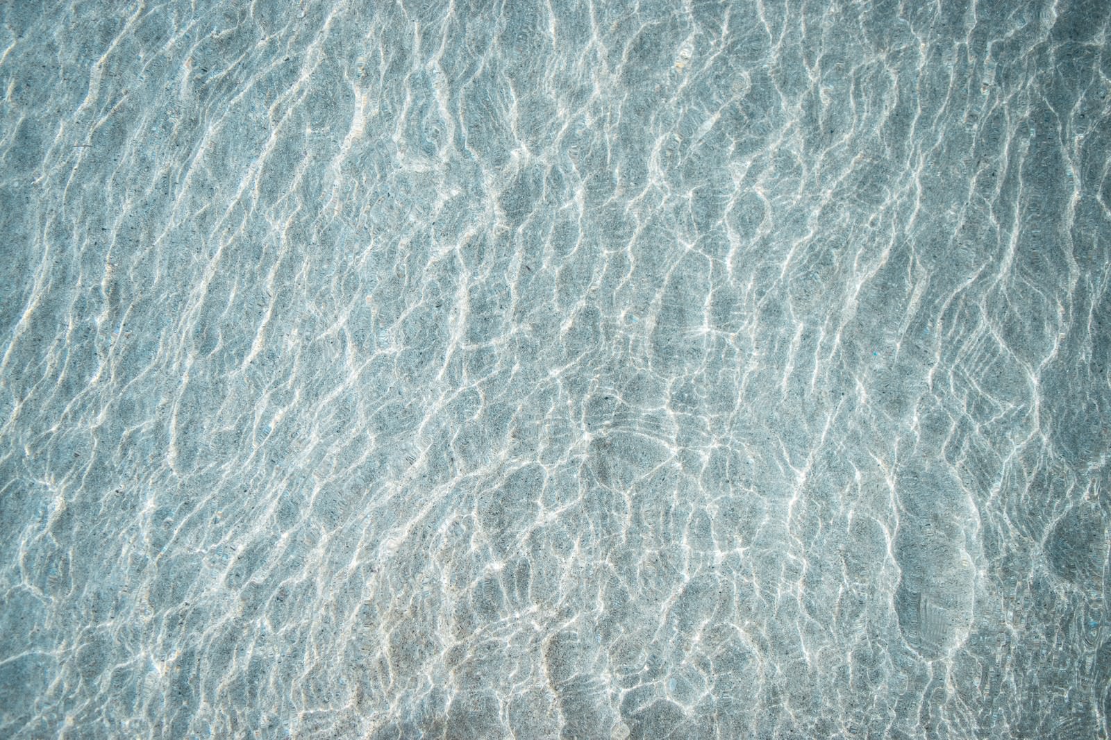 透明な浅瀬の海水を通して見える海底の砂紋