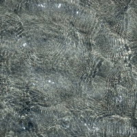 砂浜に寄せる波が作る砂と水面のテクスチャの写真