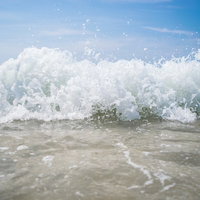 砂浜に打ち寄せる波しぶきが上がる波打ち際の写真