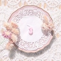 淡いピンク色のアンティークな皿に立つ数字の「3」の写真