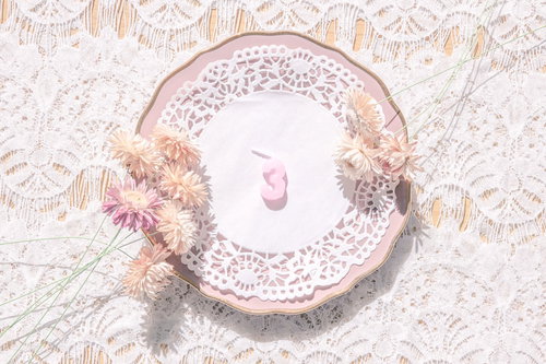 淡いピンク色のアンティークな皿に立つ数字の「3」