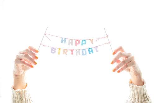 カラフルなHAPPY BIRTHDAYの文字を両手で掲げる