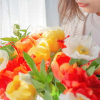 色とりどりの花束を両手で持つ女性のプレゼントの写真