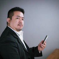 デスクサイドでスマホを操作するキリッとしたビジネスマンの写真