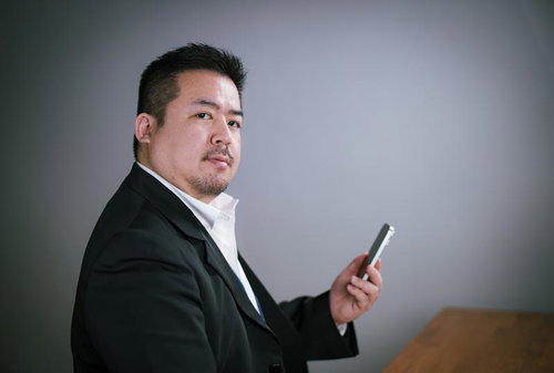 デスクサイドでスマホを操作するキリッとしたビジネスマン