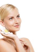 右手に乗せた白い花を頬に寄せるモデルの外国人女性の写真