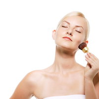 チークブラシで丁寧にメイクする金髪の外国人女性の写真