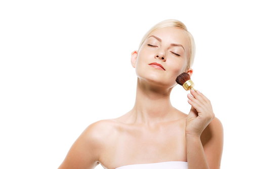 チークブラシで丁寧にメイクする金髪の外国人女性