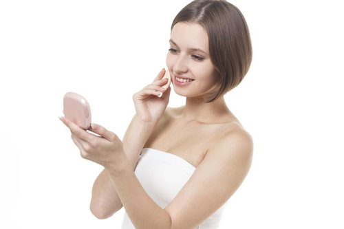 化粧直し中にコンパクトミラーで自分の顔を確認する女性