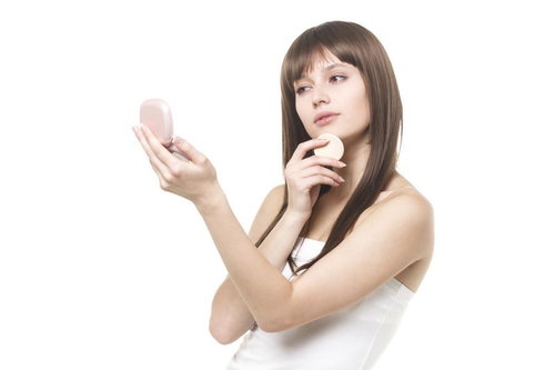 パフで化粧直しをする女性
