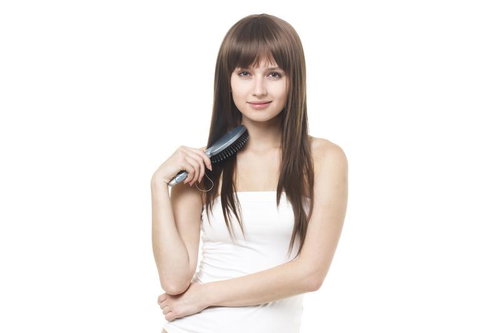 ヘアブラシで髪をとかすロングヘアの女性