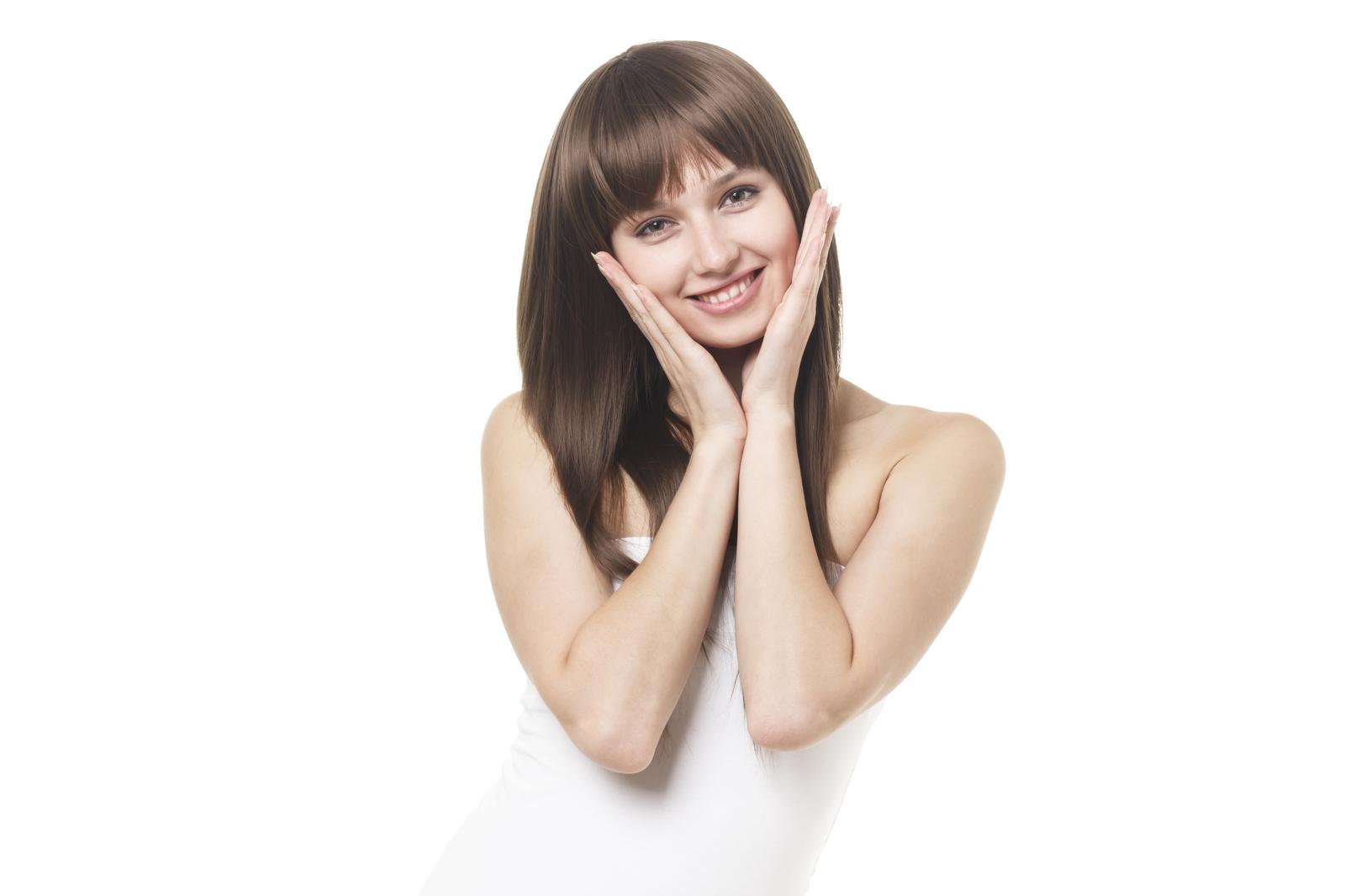 白背景の前で両手を頬に添えて笑顔を見せるストレートヘアの女性［モデル：モデルファクトリー］