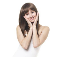 両手で頬を包んで微笑む女性の写真