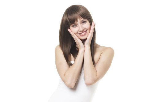 両手で頬を包んで微笑む女性