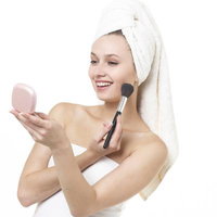 コンパクトミラーを見ながらチークを塗る女性の写真