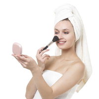 コンパクトミラーを見ながらメイクする女性の写真