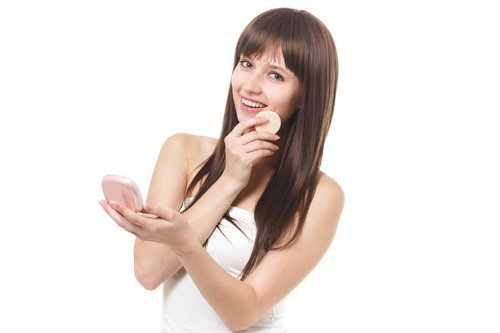 白いキャミソールを着て手鏡を見ながら微笑む女性