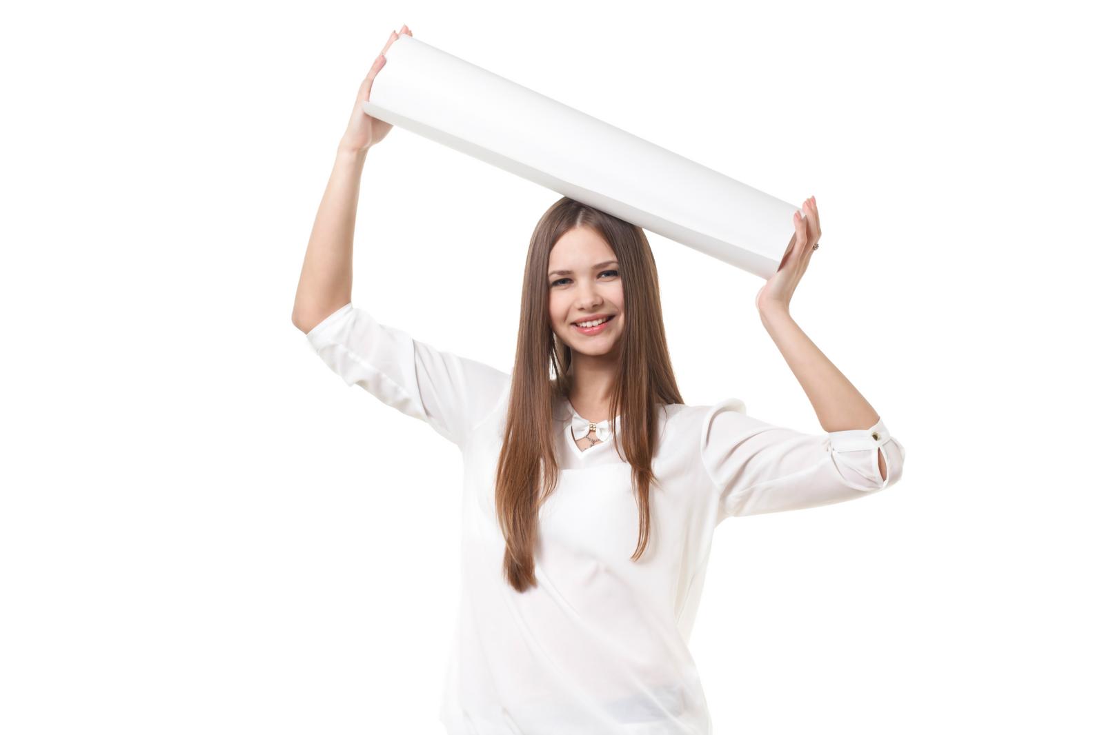 A smiling woman with long hair holding a white board raised above her head with both hands.
