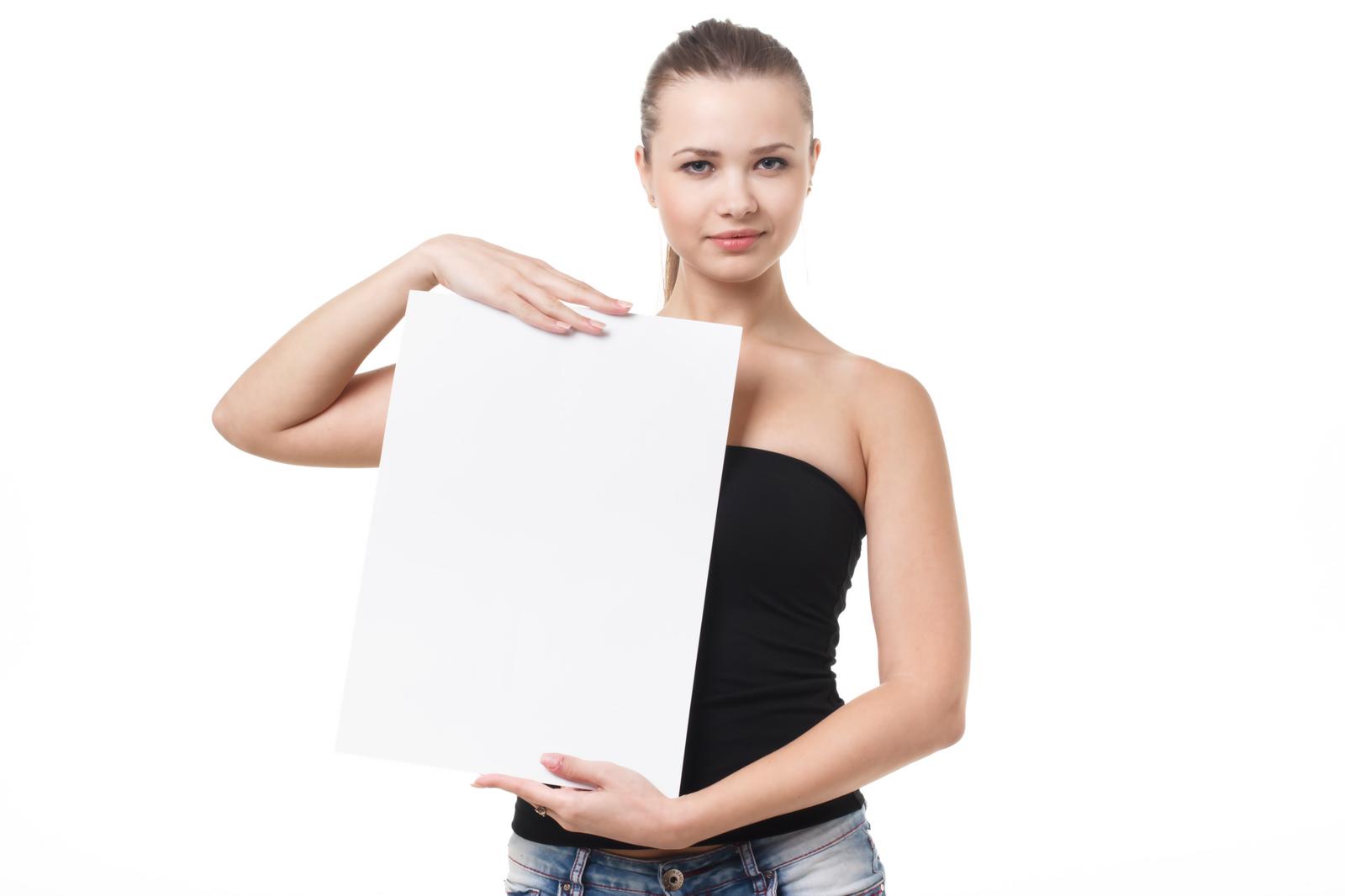 Woman in a black bandeau top and denim pants holding a white panel and posing