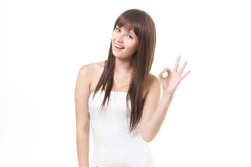 白いベアトップを着て笑顔でOKサインをする長髪の女性