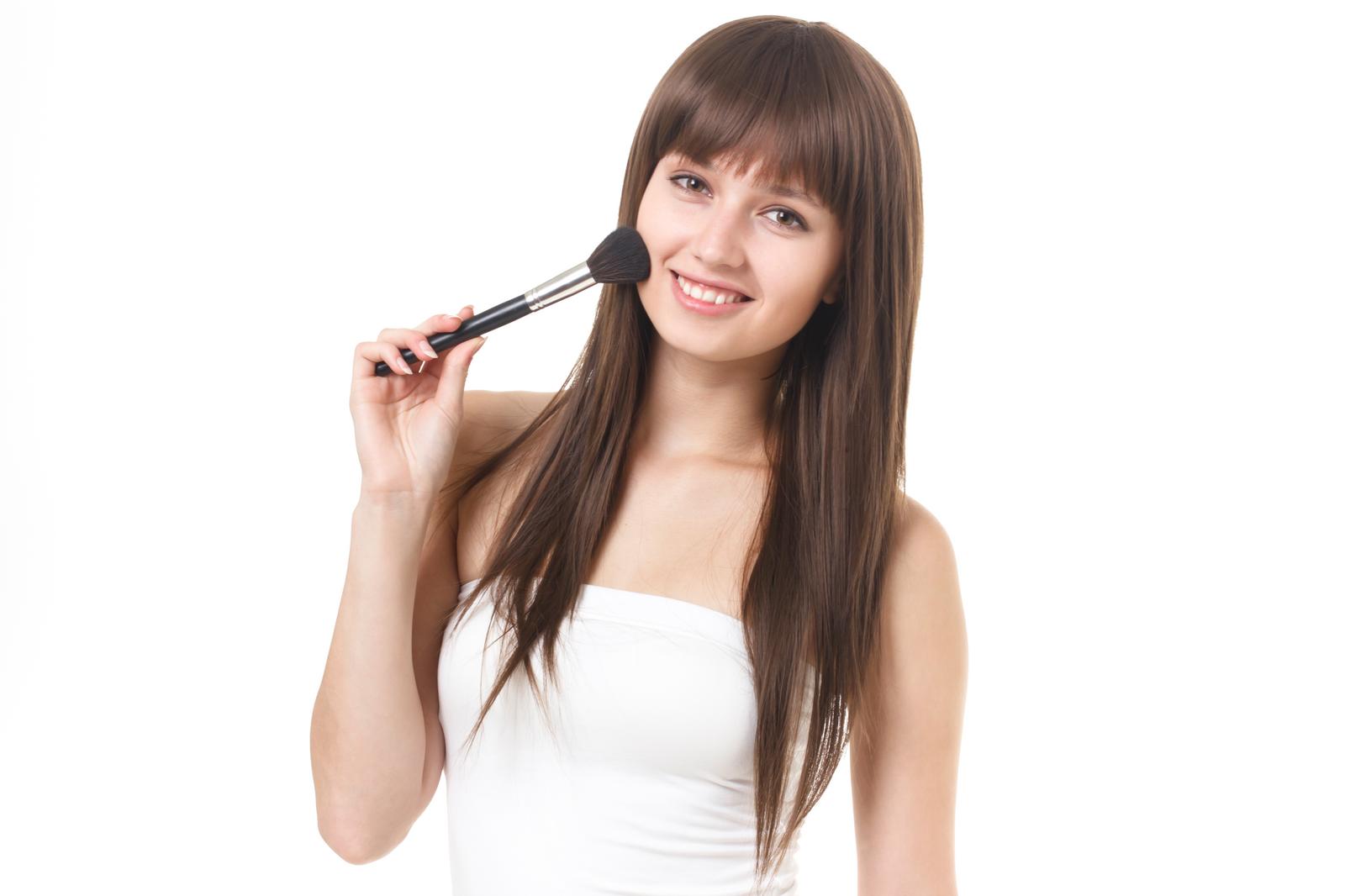 Portrait of a smiling woman in a white top carrying a make-up brush with a black handle on her shoulder