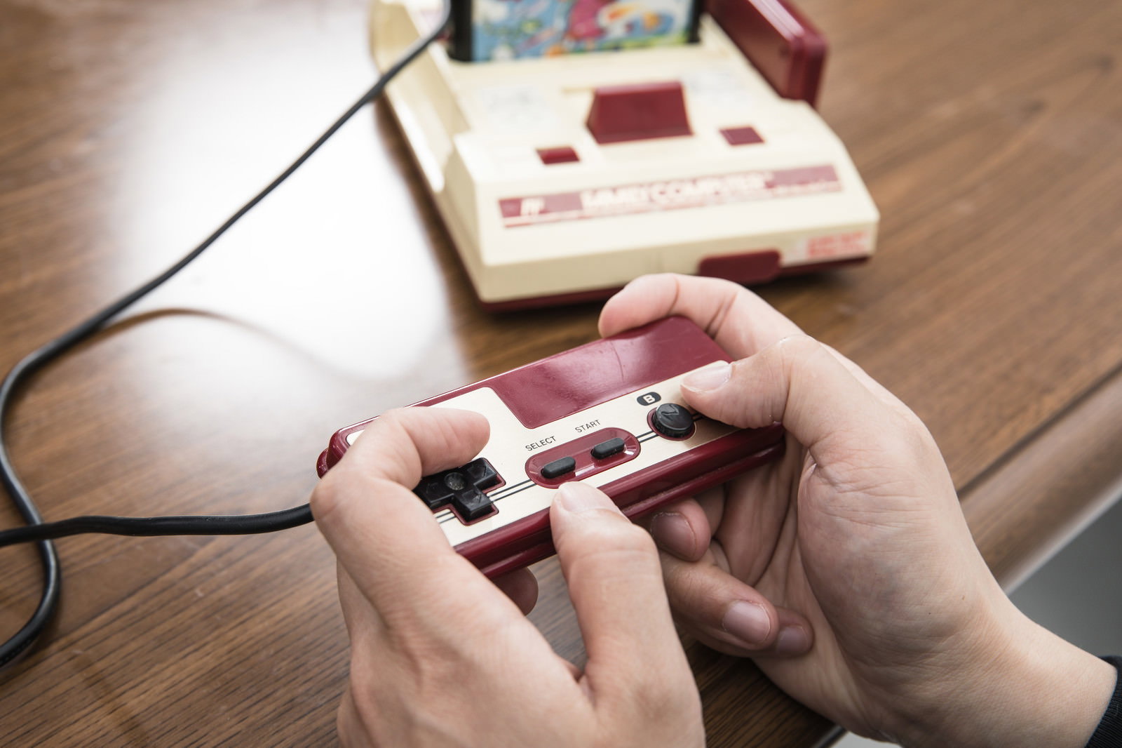 ファミコンのコントローラーを両手で握ってゲームをする手［モデル：大川竜弥］