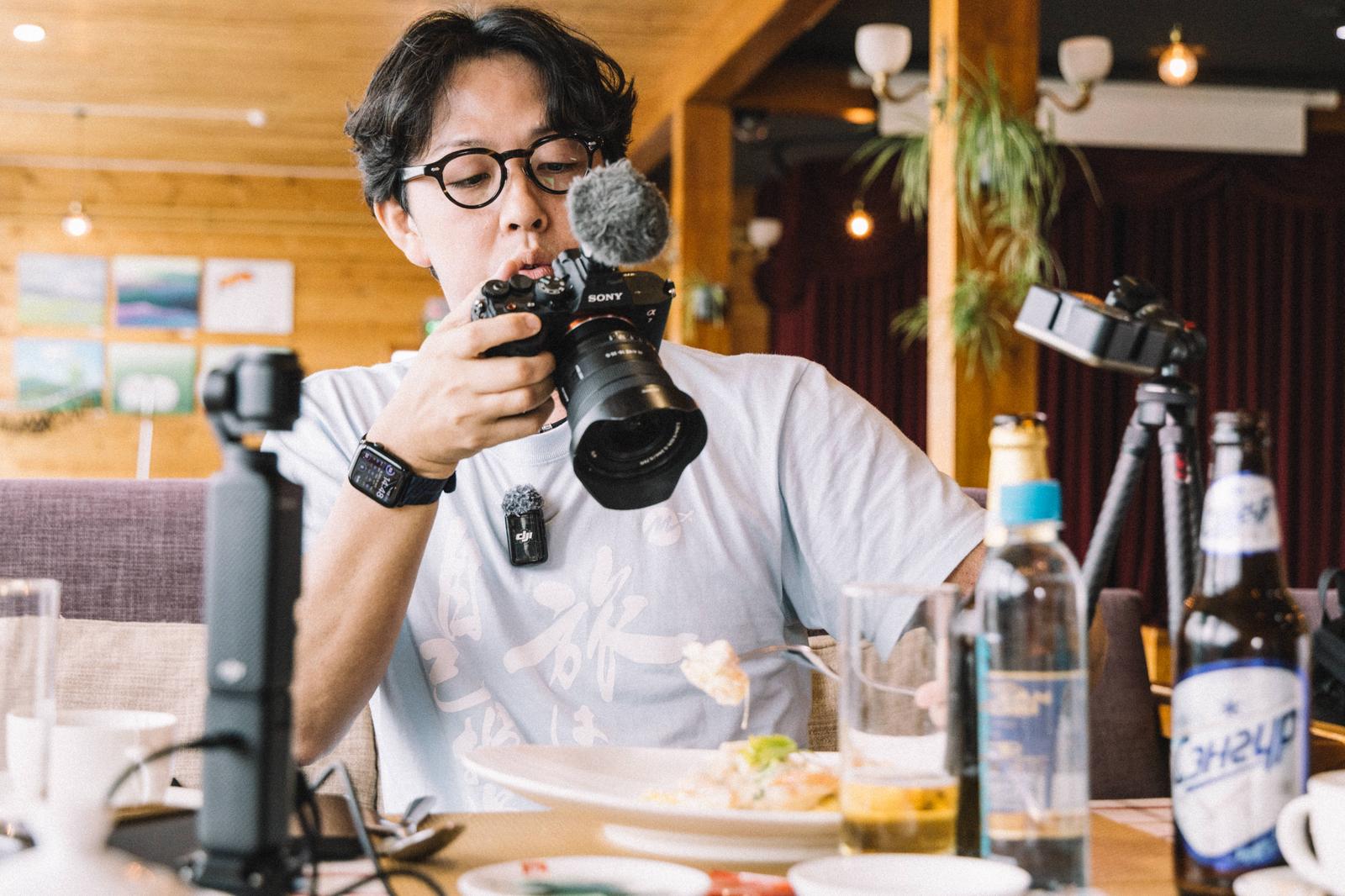 ソニーのミラーレスカメラで食事を撮影する眼鏡をかけた男性［モデル：もーりー］