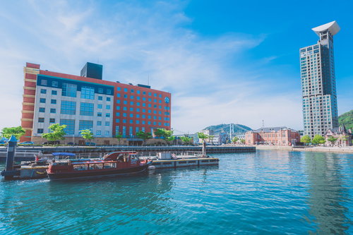 門司港レトロの船着場と遊覧船、赤と白の建築と港の風景