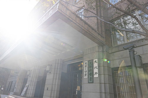 日が射す文部科学省の建物外観と柱列