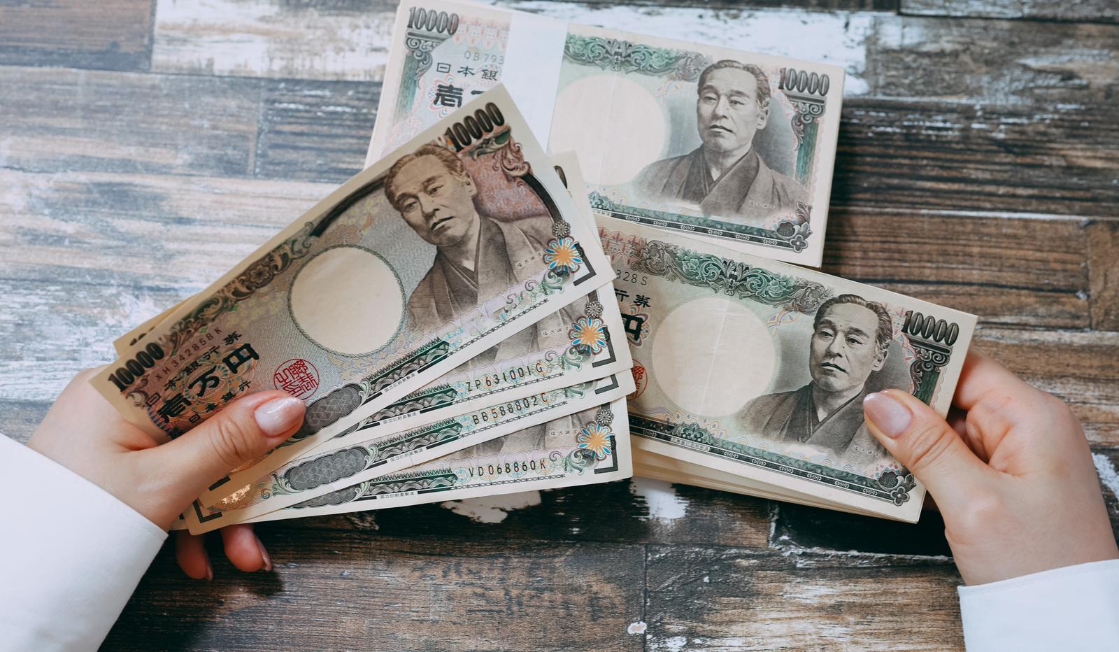 両手で一万円札を扇形に広げて見せている