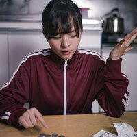 買ったレシートとお釣りの小銭が合わない女性の写真