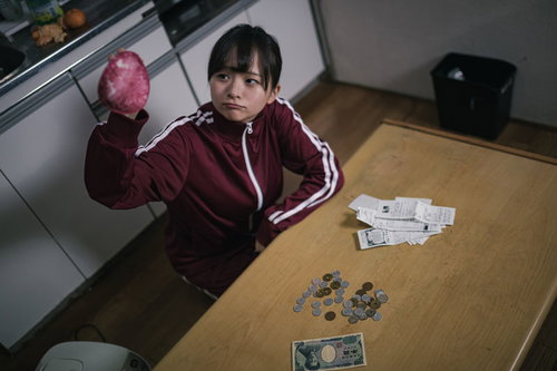 失業して貧困に陥った女性がワンルームで座り込む