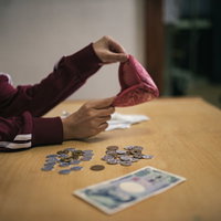 今月の生活費はこれで全部、テーブルに散らばる小銭と千円札の写真