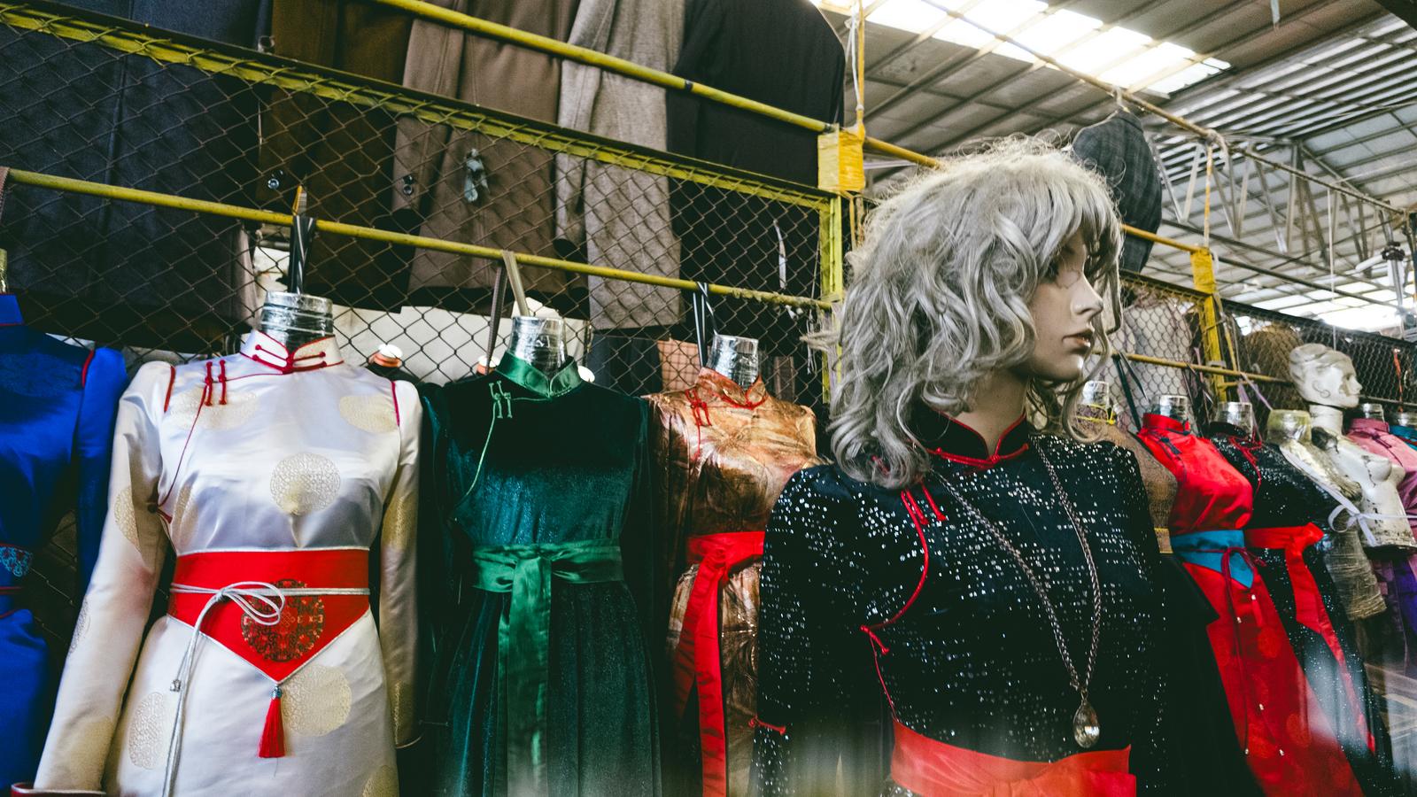 モンゴルの市場でグレーのかつらを被ったマネキンとカラフルな衣服が並ぶ様子
