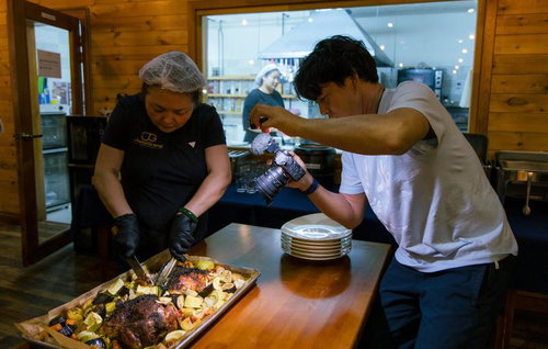 厨房で肉料理を撮影するYouTuberと調理する料理人