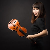 黒いトップスを着たヴァイオリニストの女性が琥珀色のヴァイオリンを持つの写真