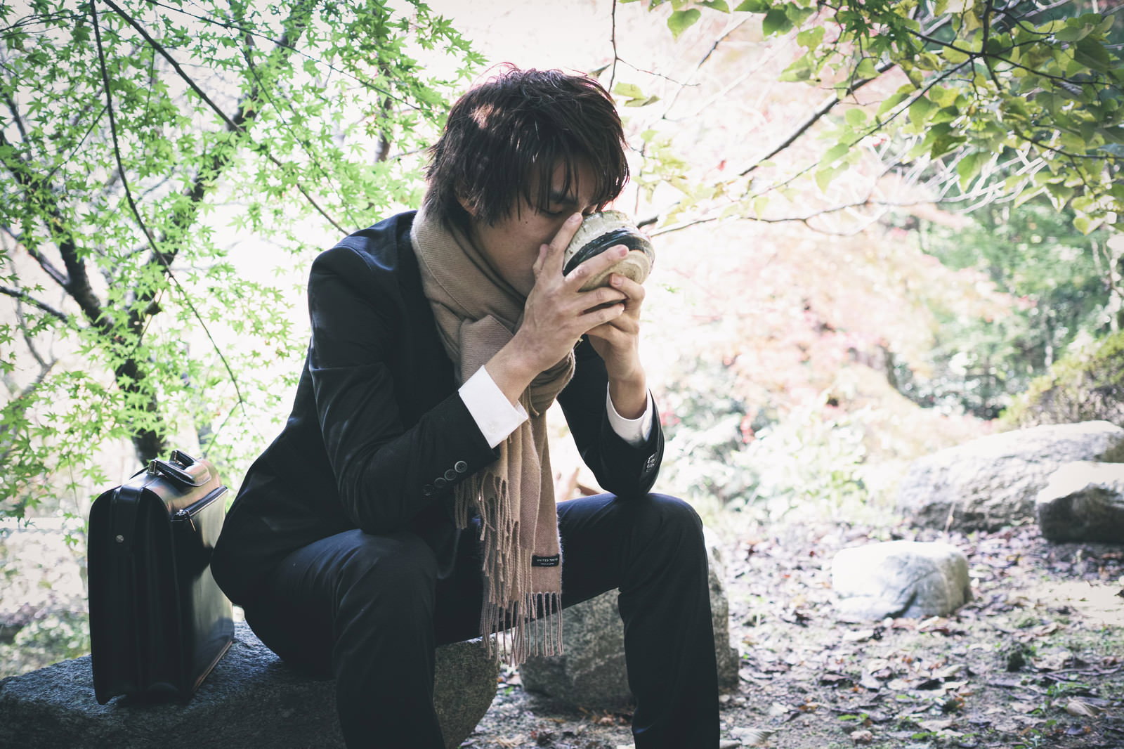 A man in a kimono sitting outdoors and sipping matcha tea