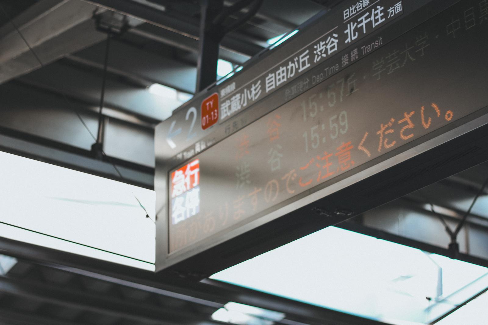 A digital display board showing train line numbers and destinations at a train station platform